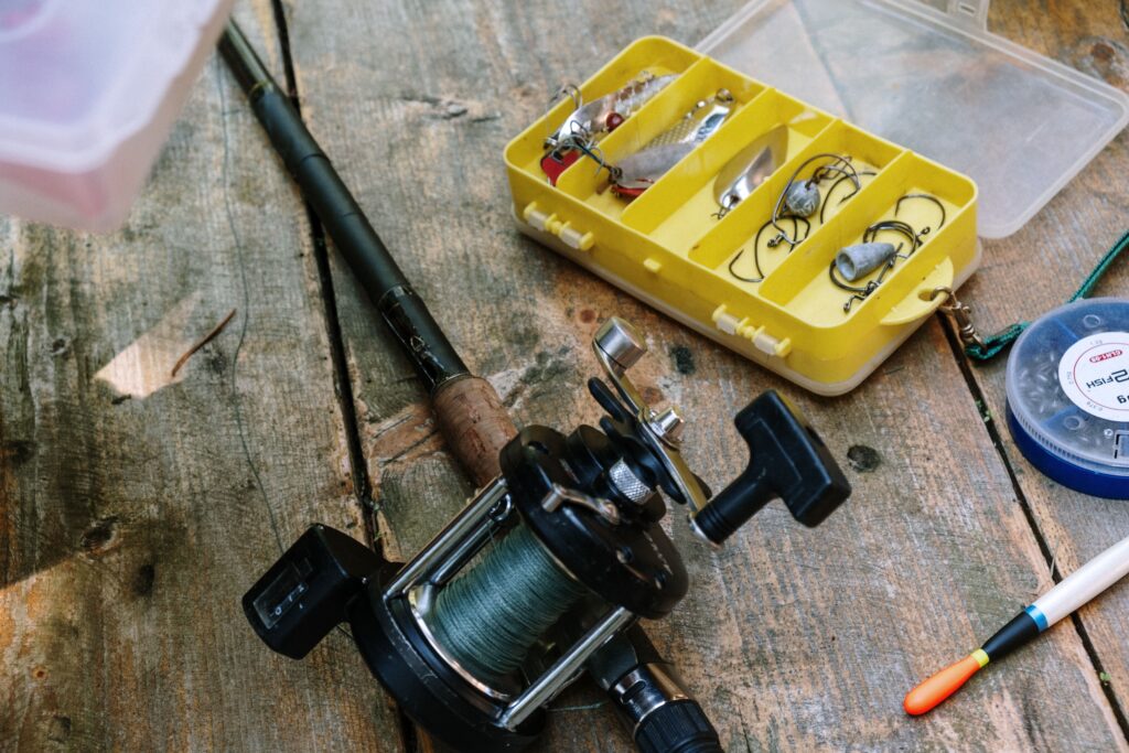 Home Close-up of fishing gear, including rod, reel, and lures on a wooden surface.